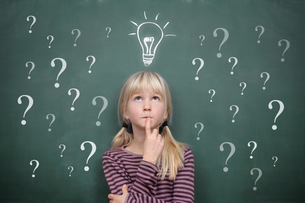 Schoolgirl at the Blackboard with Question Marks and Idea